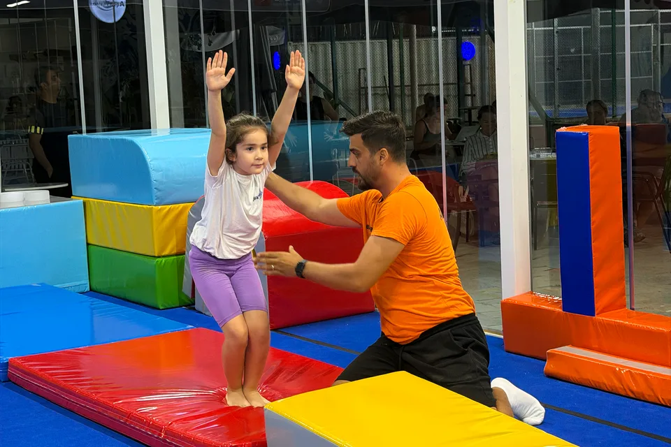 AquaWave çocuk cimnastik dersinde eğitmen destekli temel sıçrama çalışması