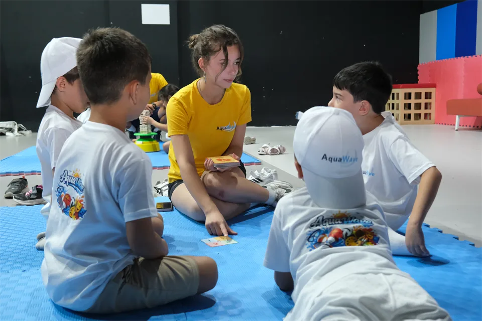 AquaWave yaz okulunda öğretmenle minder üzerinde grup etkinliği yapan çocuklar
