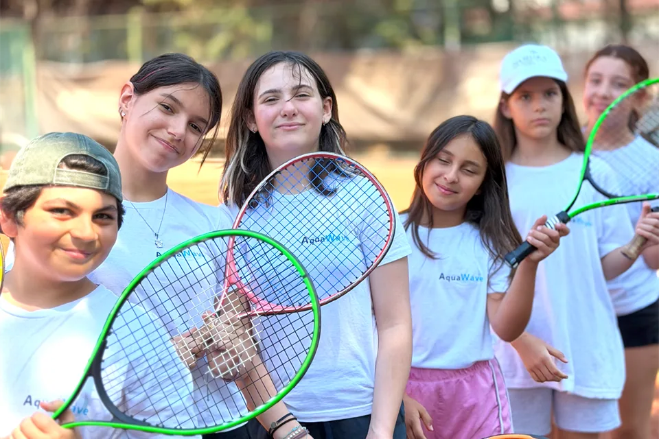 Tenis raketleriyle birlikte poz veren AquaWave yaz okulu grubu